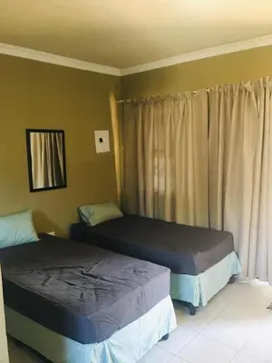 a bedroom with two beds and a window at The Hope Apartments in Nelspruit