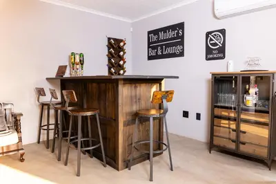 a bar with stools and a counter with wine bottles at Farmco Marloth Park in Marloth Park