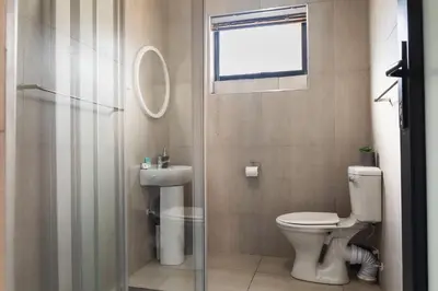 a bathroom with a toilet and a sink and a shower at Matusadona Suites in Mokopane