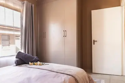 a bedroom with a bed and a large window at Matusadona Suites in Mokopane