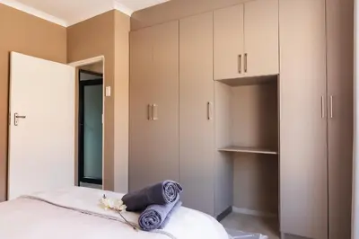 a bedroom with white cabinets and blue towels on a bed at Matusadona Suites in Mokopane