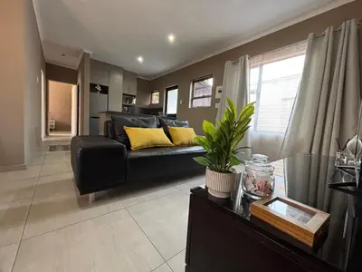 a living room with a black couch and yellow pillows at Matusadona Suites in Mokopane