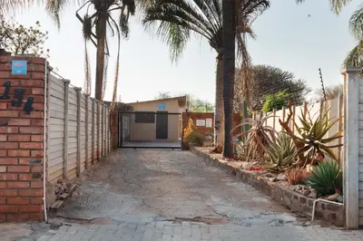 a driveway with palm trees in front of a house at Matusadona Suites in Mokopane