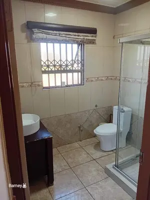a bathroom with a toilet and a sink and a window at M Palace Guest House in Kempton Park