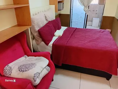 a bedroom with a red bed and a chair at M Palace Guest House in Kempton Park