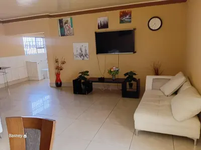a living room with a white couch and a tv at M Palace Guest House in Kempton Park