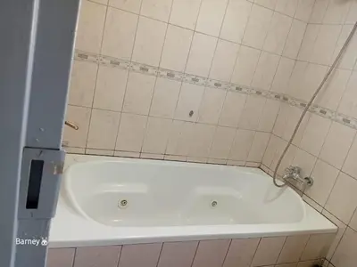 a white bath tub in a tiled bathroom at M Palace Guest House in Kempton Park