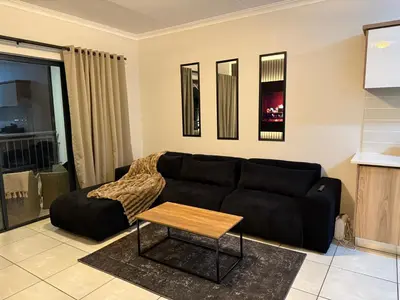 a living room with a black couch and a table at The Dream Stay At The Blyde - Suite 2 in Pretoria