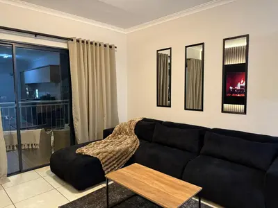 a living room with a black couch and a table at The Dream Stay At The Blyde - Suite 2 in Pretoria