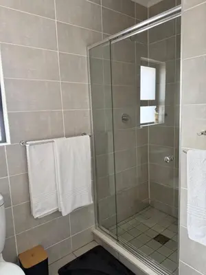 a bathroom with a glass shower with white towels at The Dream Stay At The Blyde - Suite 2 in Pretoria