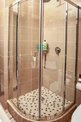 a shower with a glass door and a tile floor at Ever After Stays in Midrand