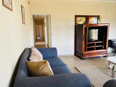 a living room with a blue couch and a tv at Bird & Bed Farmhouse in Brits