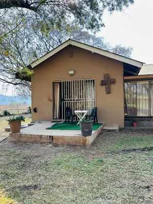 a small house with a green lawn in front of it at Bird & Bed Farmhouse in Brits
