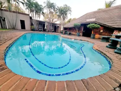 a large swimming pool with blue water in a yard at Sundown Lodge in Komatipoort