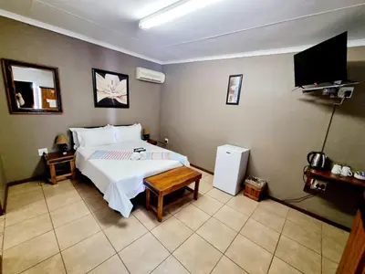 a bedroom with a bed and a flat screen tv at Sundown Lodge in Komatipoort