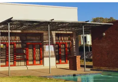 a library with red doors and a pool in front of it at Carlswald Luxe in Midrand