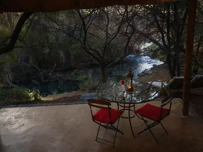 a glass table with two chairs and a river at Lethabo Estate in Lanseria