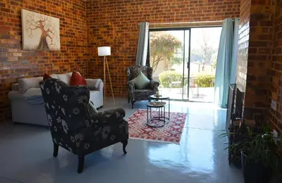 a living room with two chairs and a brick wall at Dullight Self Cater Cottage in Dullstroom