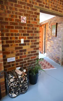 a brick wall with a pile of logs and a plant at Dullight Self Cater Cottage in Dullstroom