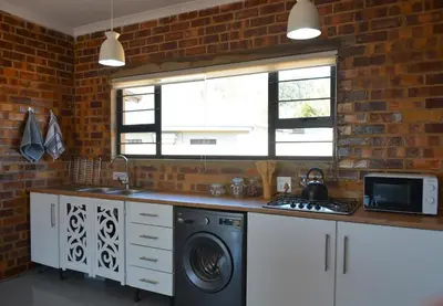 a kitchen with a washing machine and a brick wall at Dullight Self Cater Cottage in Dullstroom