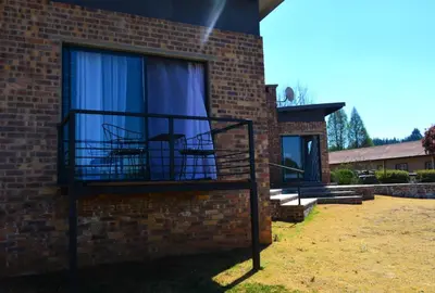 a balcony with two chairs in a brick building at Dullight Self Cater Cottage in Dullstroom