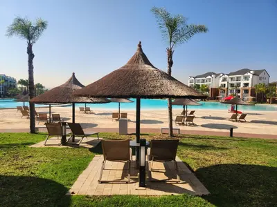 a table with chairs and umbrellas next to a beach at Luxury Apartment - The Blyde Crystal Lagoon in Pretoria