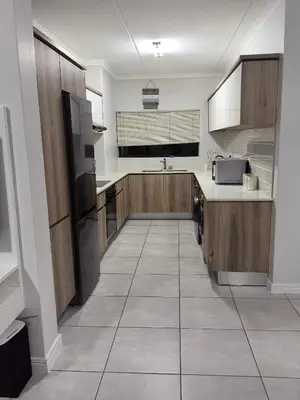 a large kitchen with wooden cabinets and a tile floor at Luxury Apartment - The Blyde Crystal Lagoon in Pretoria