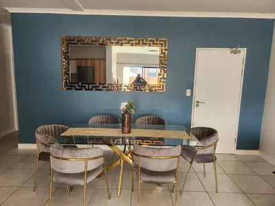 a dining room with a table and chairs and a mirror at Luxury Apartment - The Blyde Crystal Lagoon in Pretoria