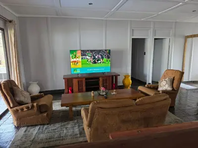 a living room with a tv and a table and chairs at Nandoni Maritime Home in Thohoyandou