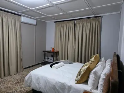 a bedroom with a bed with white sheets and gold pillows at Nandoni Maritime Home in Thohoyandou
