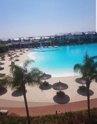 a large swimming pool with umbrellas and palm trees at The Corinthians Lagoon facing in Pretoria