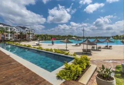 a pool at a resort with tables and umbrellas at The Corinthians Lagoon facing in Pretoria
