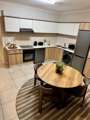 a kitchen with a wooden table and chairs in a kitchen at The Corinthians Lagoon facing in Pretoria