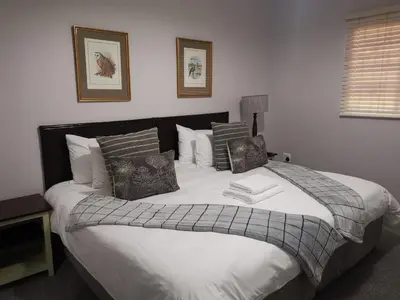 a bedroom with a large bed with white sheets and pillows at Valyspruit Trout Fishing and Game Retreat in Dullstroom