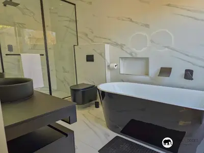 a bathroom with a tub and a glass shower at 99 on Zwartkloof - Luxury Bushveld Retreat in Warmbaths