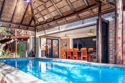 an indoor pool with orange chairs and a house at Bartlett Safari Marloth Park in Marloth Park