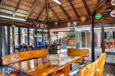 a dining room with a large wooden table and chairs at Bartlett Safari Marloth Park in Marloth Park