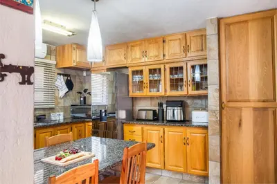 a kitchen with wooden cabinets and a table with chairs at Bartlett Safari Marloth Park in Marloth Park