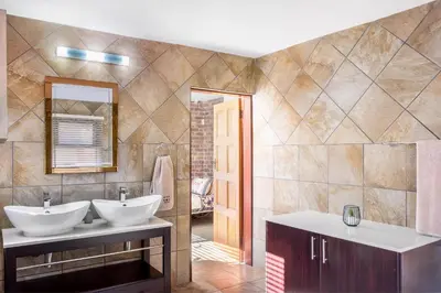 a bathroom with two sinks and a mirror at Bartlett Safari Marloth Park in Marloth Park
