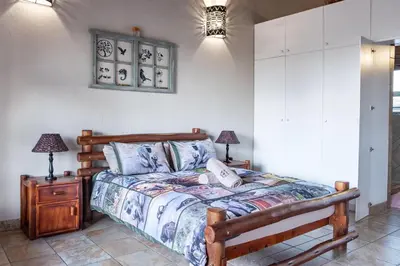 a bedroom with a bed and a nightstand with two lamps at Bartlett Safari Marloth Park in Marloth Park