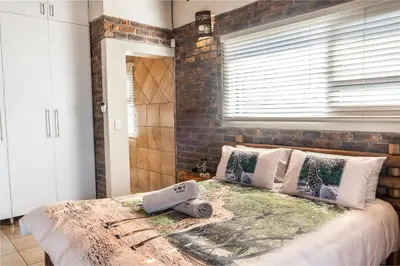 a bedroom with a large bed with a brick wall at Bartlett Safari Marloth Park in Marloth Park