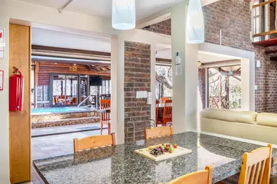 a dining room with a table and chairs and a couch at Bartlett Safari Marloth Park in Marloth Park