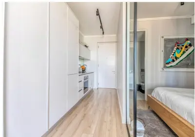 a bedroom with white walls and a bed and a kitchen at Modern Bachelor Suite & Stunning View Pool & Gym in Midrand