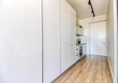 a kitchen with white cabinets and a hardwood floor at Modern Bachelor Suite & Stunning View Pool & Gym in Midrand