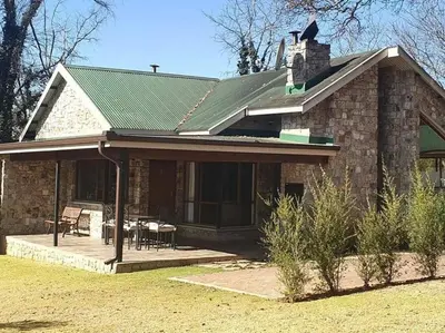 a brick house with a green roof and a patio at Big Oak Cottages in Dullstroom
