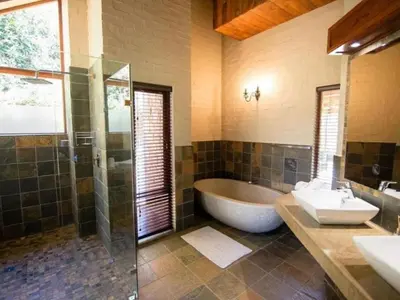 a bathroom with a tub and a sink and a shower at Big Oak Cottages in Dullstroom