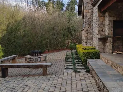 a brick patio with a bench and a stone building at Big Oak Cottages in Dullstroom