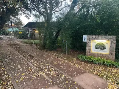 a sign in front of a building with a tree at Big Oak Cottages in Dullstroom
