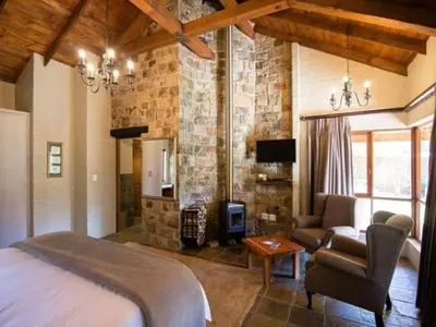 a bedroom with a bed and a stone wall at Big Oak Cottages in Dullstroom