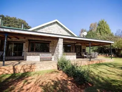 a stone house with a porch and a patio at Big Oak Cottages in Dullstroom